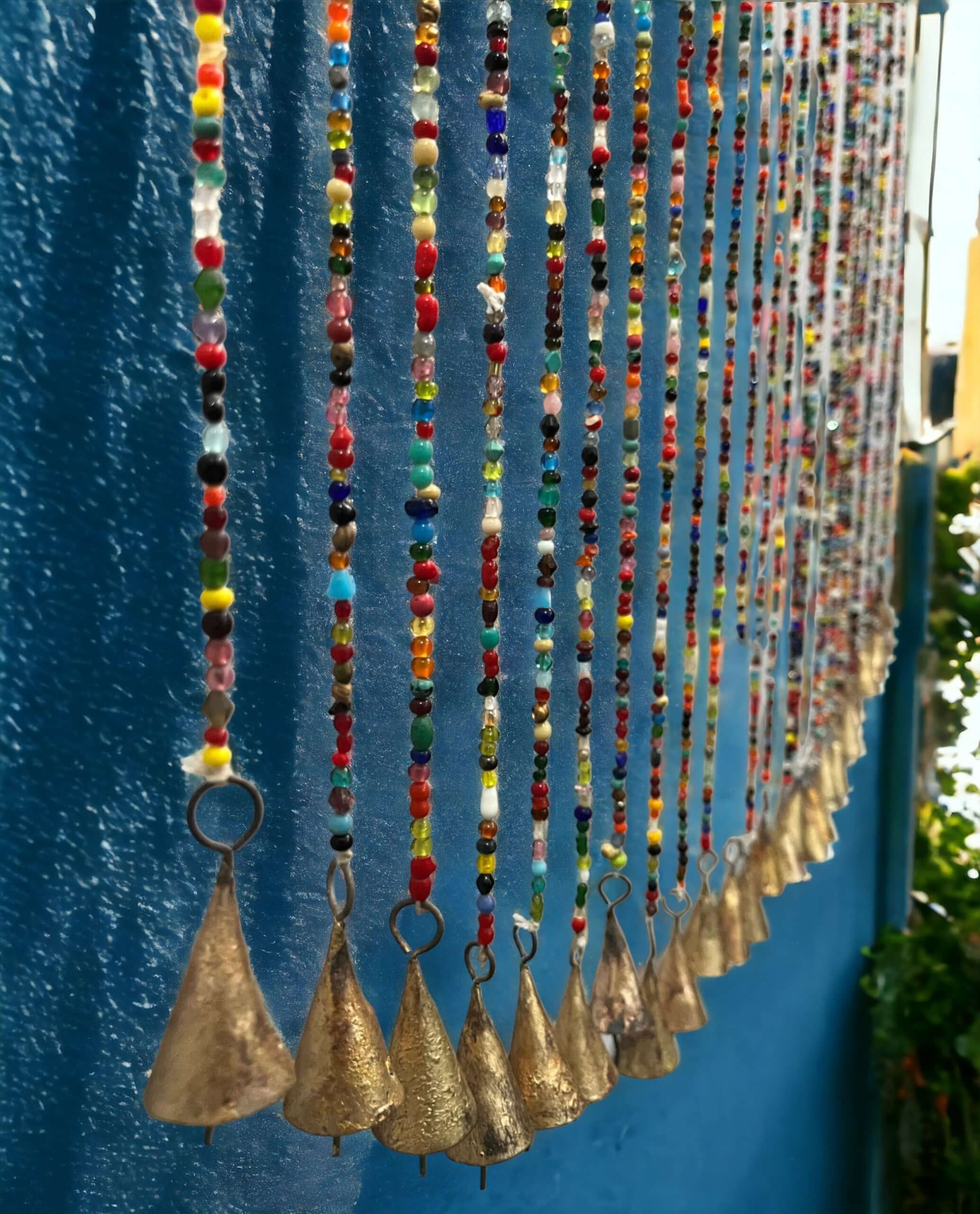 Colorful bohemian glass beaded curtain with gold bells, perfect for hippie decor and doorways.